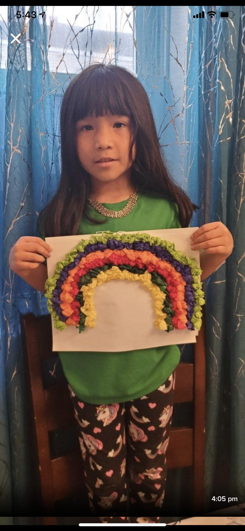 girl holding paper mache rainbow