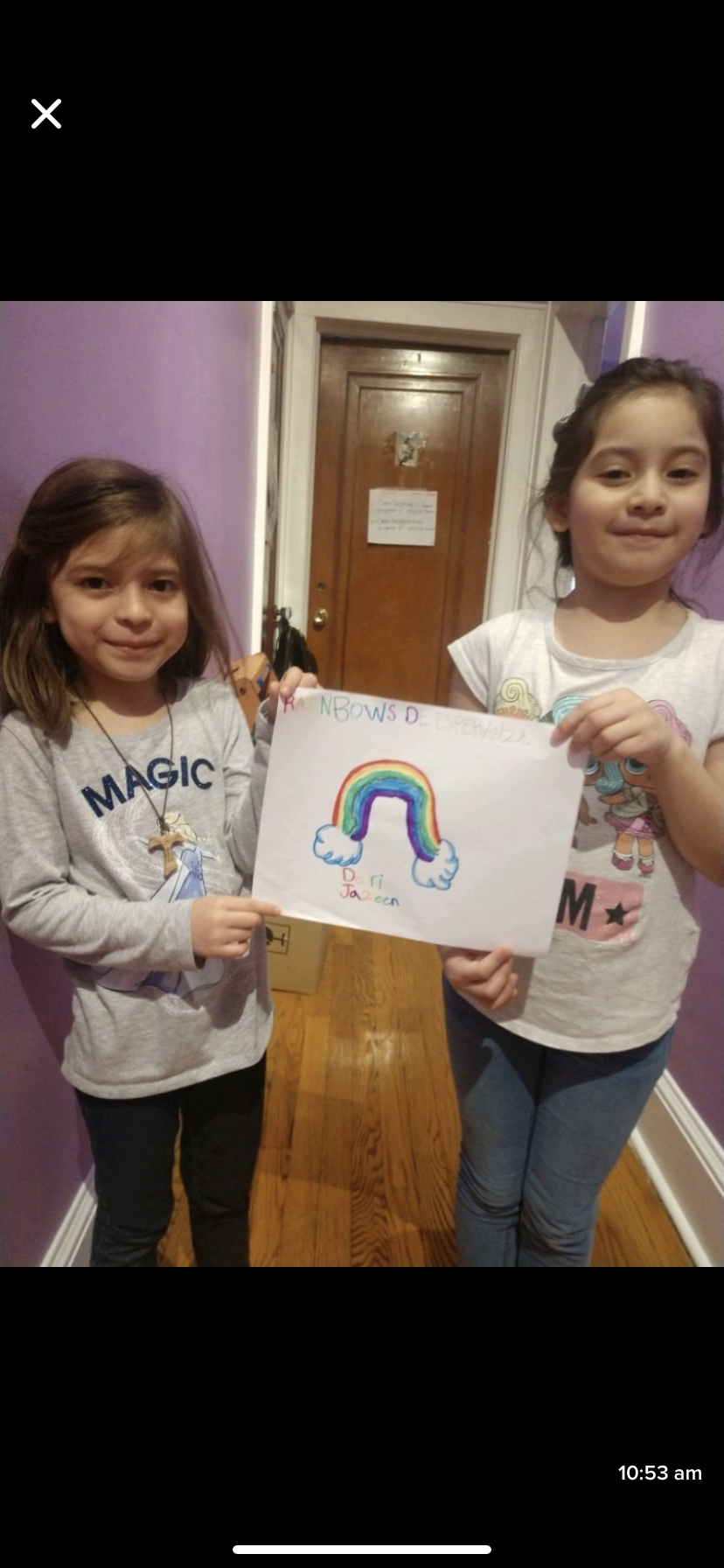 sisters holding up rainbow drawing in their hallway