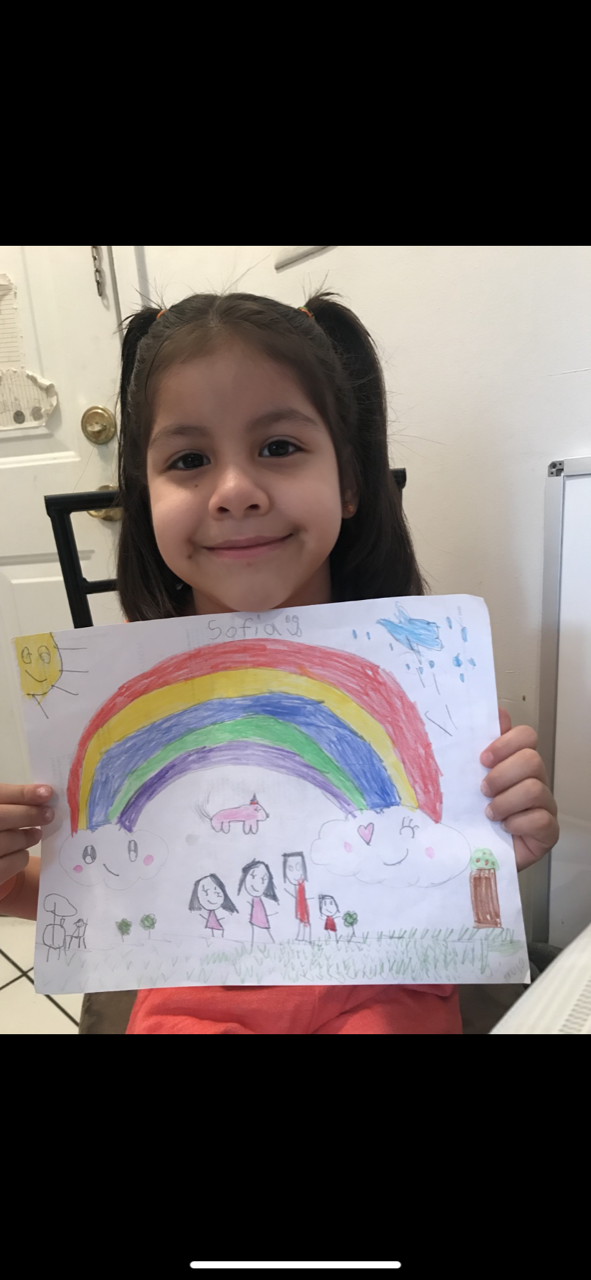 girl showing off her rainbow drawing with her family underneath
